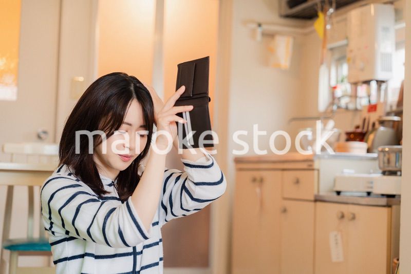 財布の中を確認して落ち込む若い女性