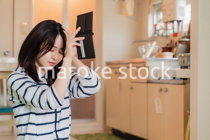 財布の中を確認して落ち込む若い女性