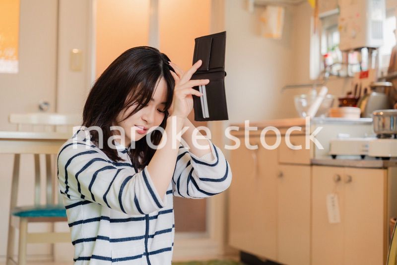 財布の中を確認して落ち込む若い女性