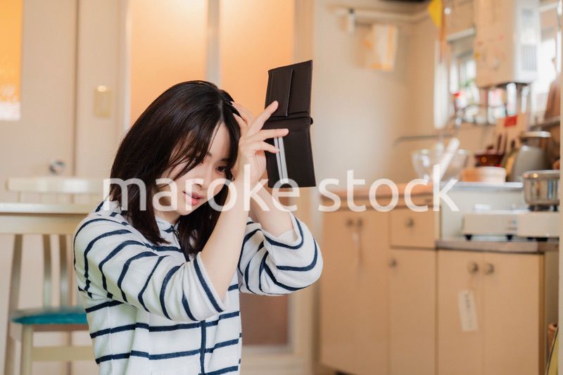 財布の中を確認して落ち込む若い女性