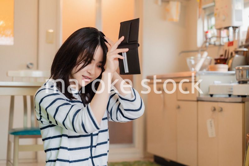 財布の中を確認して落ち込む若い女性