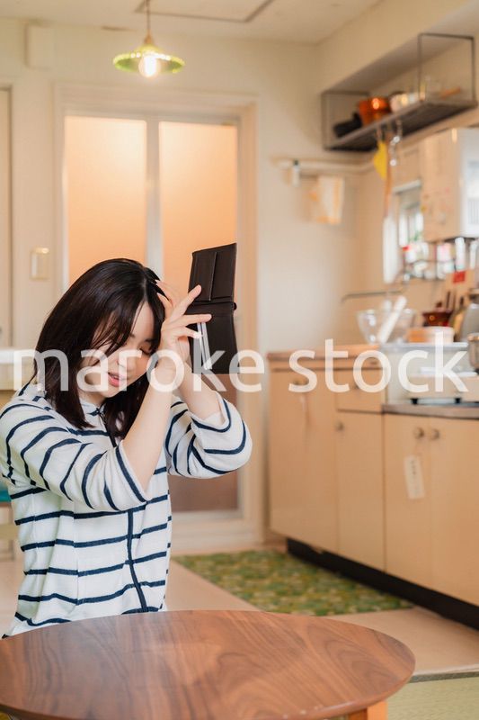 財布の中を確認して落ち込む若い女性