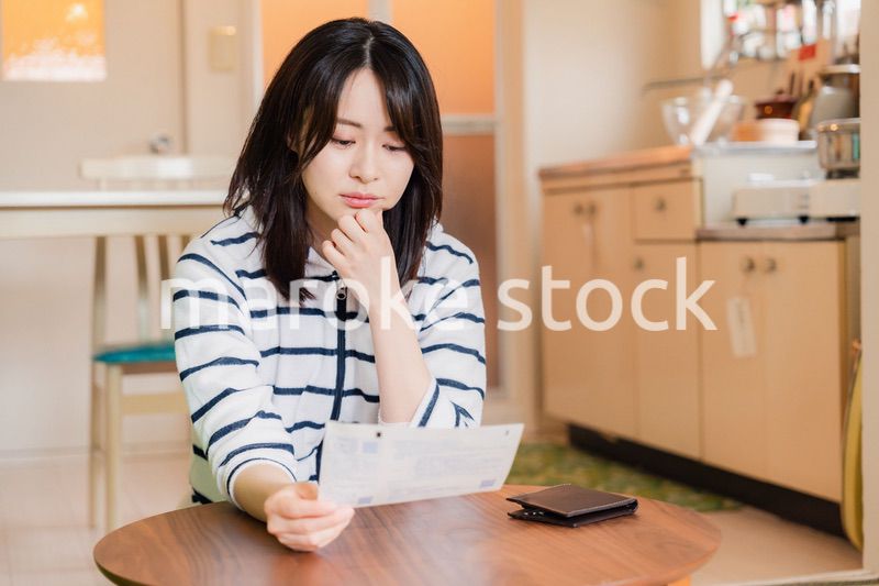 電気料金の高騰で頭を抱える若い女性
