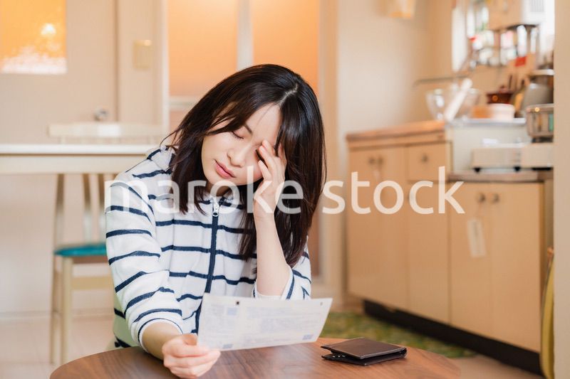 電気料金の高騰で頭を抱える若い女性