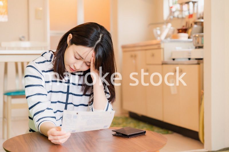 電気料金の高騰で頭を抱える若い女性