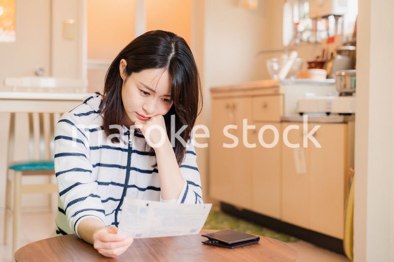電気料金の高騰で頭を抱える若い女性