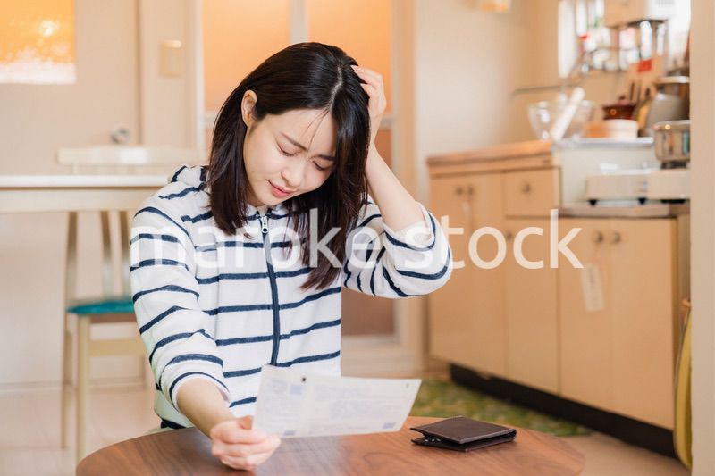 電気料金の高騰で頭を抱える若い女性