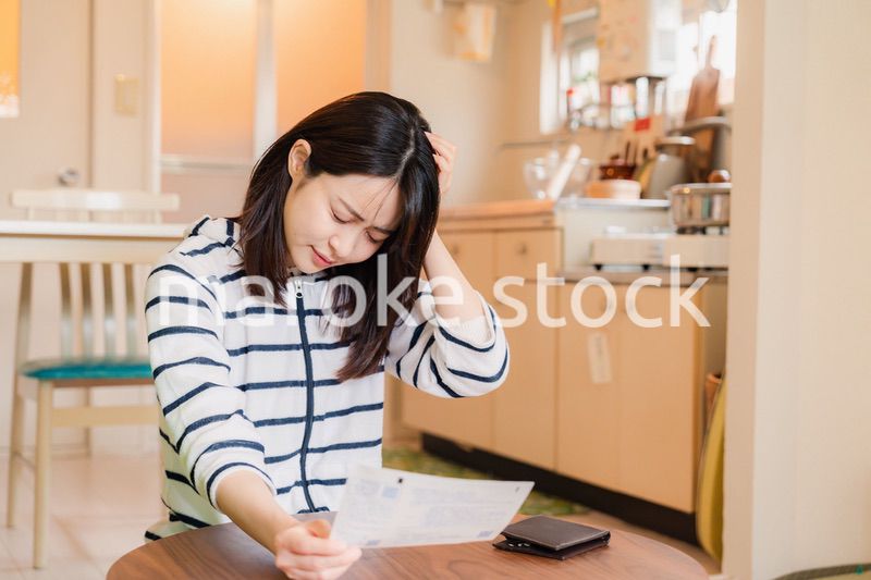 電気料金の高騰で頭を抱える若い女性
