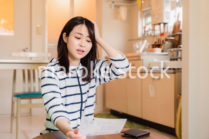 電気料金の高騰で頭を抱える若い女性