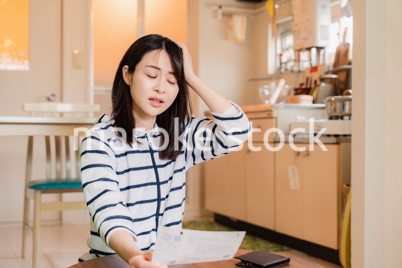電気料金の高騰で頭を抱える若い女性