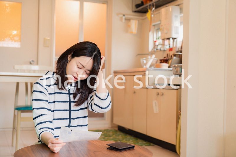 電気料金の高騰で頭を抱える若い女性