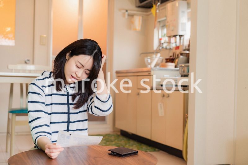 電気料金の高騰で頭を抱える若い女性