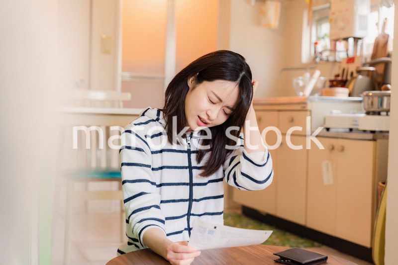 電気料金の高騰で頭を抱える若い女性