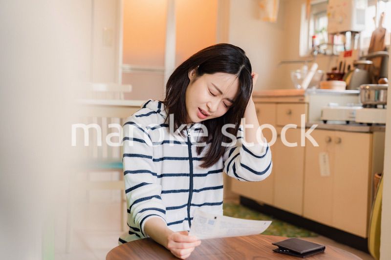 電気料金の高騰で頭を抱える若い女性