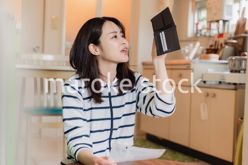 財布の中を確認して落ち込む若い女性