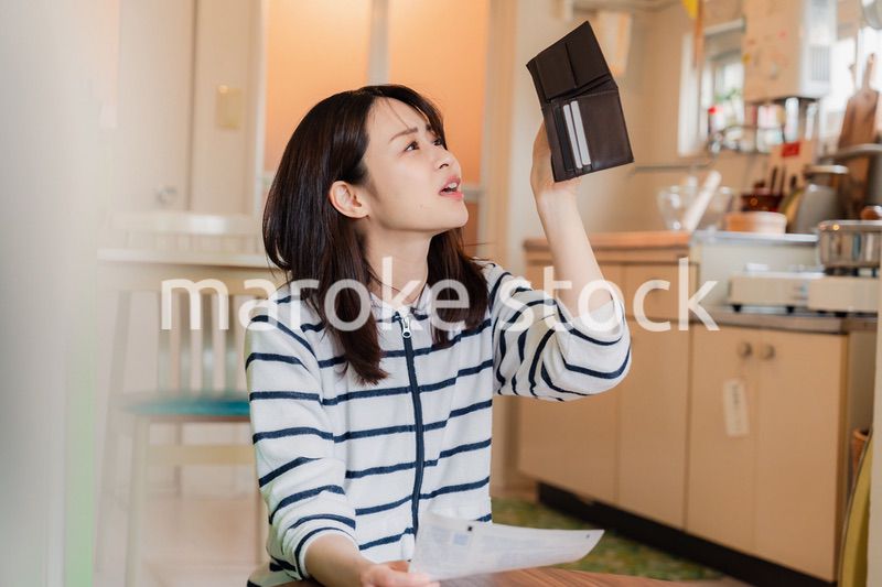 財布の中を確認して落ち込む若い女性
