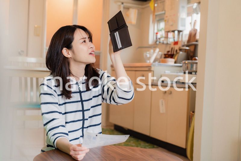 財布の中を確認して落ち込む若い女性