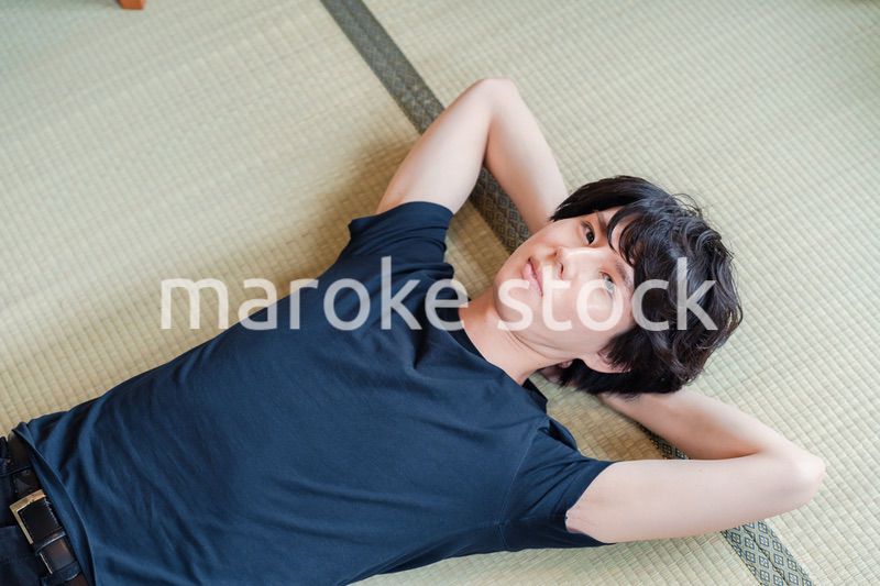 畳の上で寝転がる若い男性