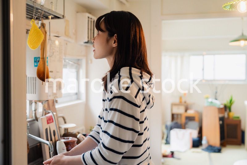 団地の台所で家事をする女性