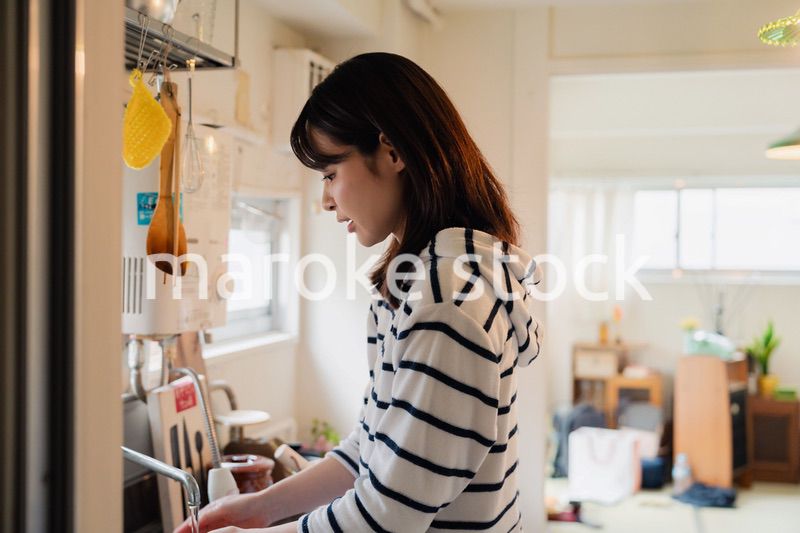 団地の台所で家事をする女性