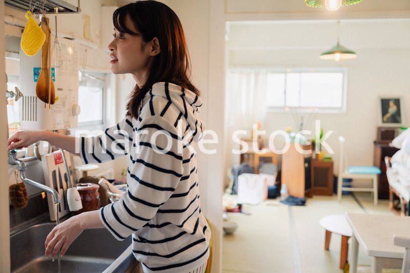 団地の台所で家事をする女性