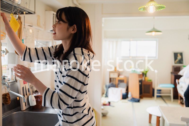 団地の台所で家事をする女性