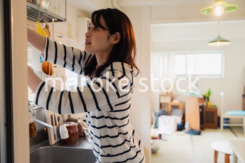 団地の台所で家事をする女性