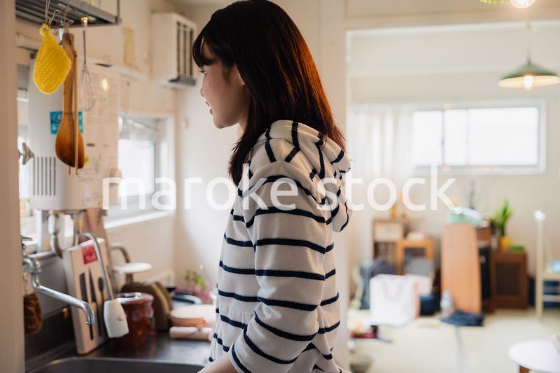 団地の台所で家事をする女性