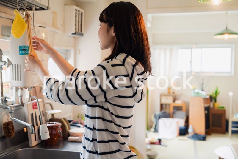団地の台所で家事をする女性