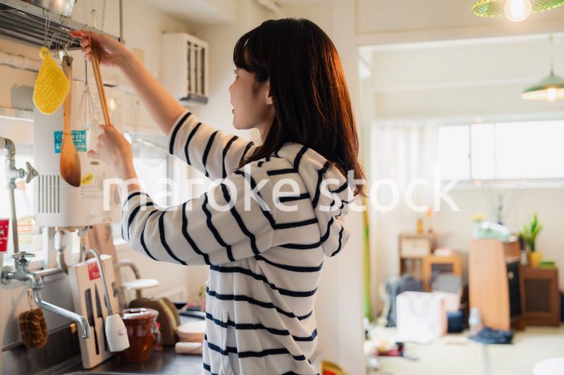 団地の台所で家事をする女性
