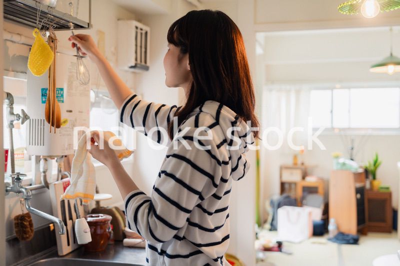 団地の台所で家事をする女性