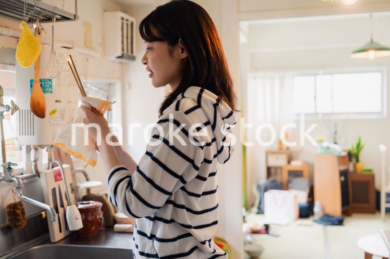 団地の台所で家事をする女性