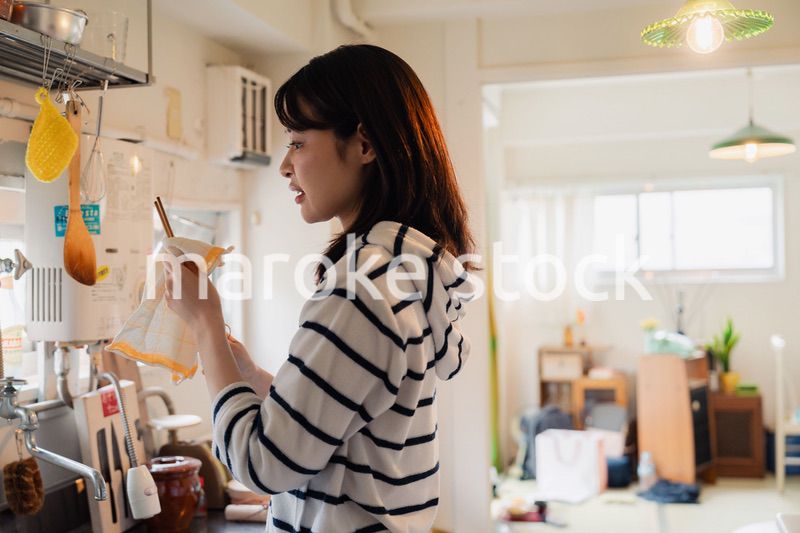団地の台所で家事をする女性