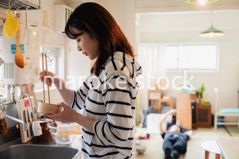 妻がお弁当を作っている後ろで寝転ぶ夫