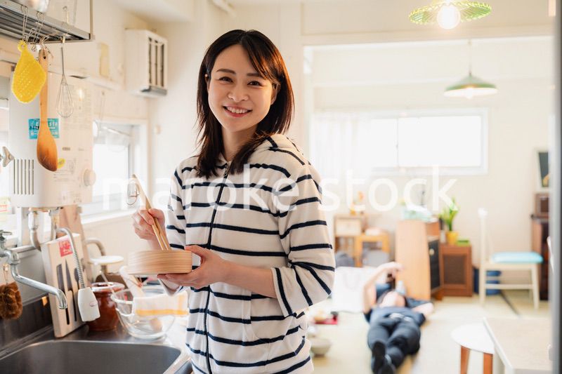 妻がお弁当を作っている後ろで寝転ぶ夫