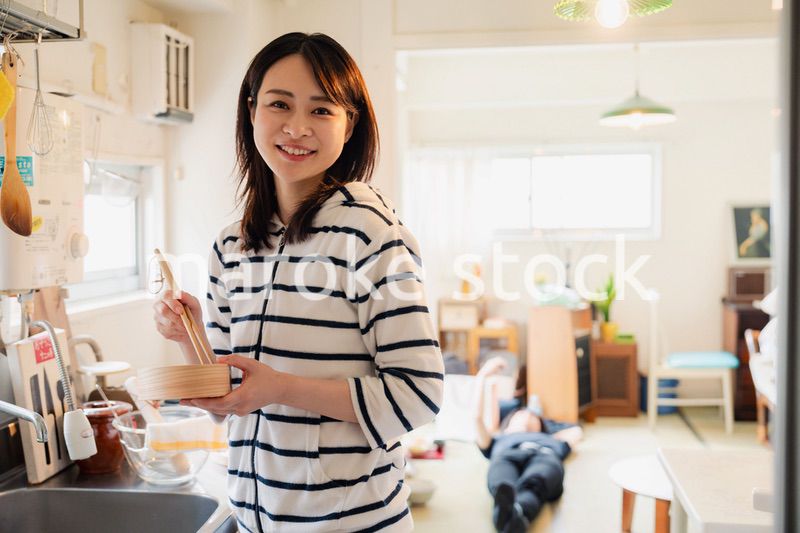 妻がお弁当を作っている後ろで寝転ぶ夫