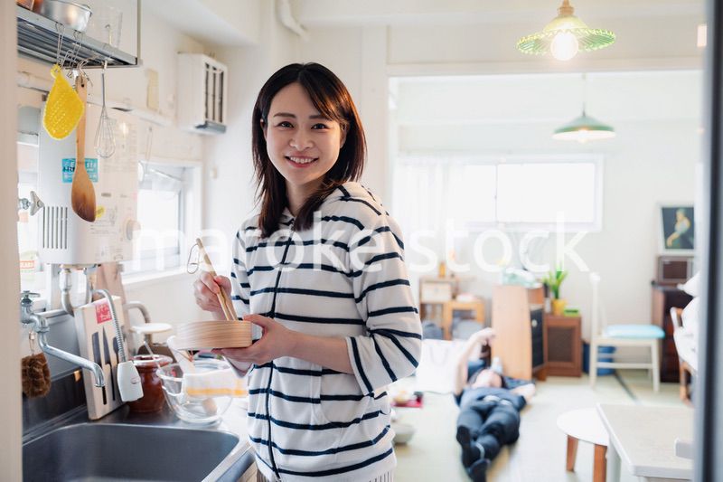 妻がお弁当を作っている後ろで寝転ぶ夫