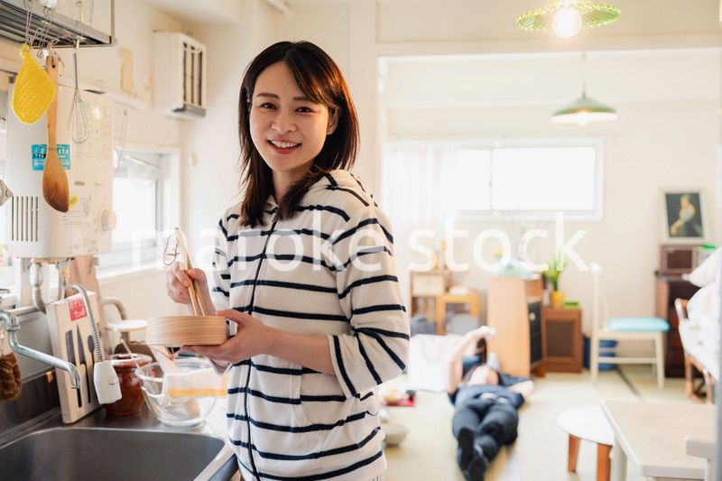 妻がお弁当を作っている後ろで寝転ぶ夫