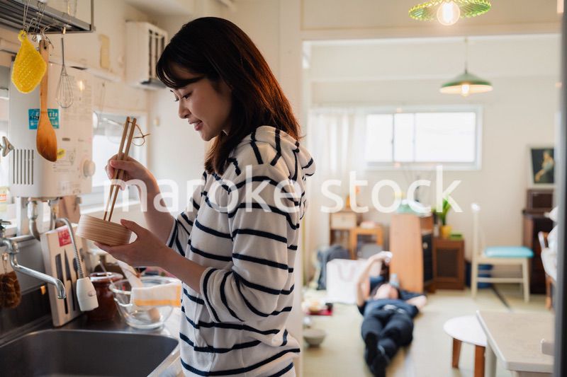 妻がお弁当を作っている後ろで寝転ぶ夫
