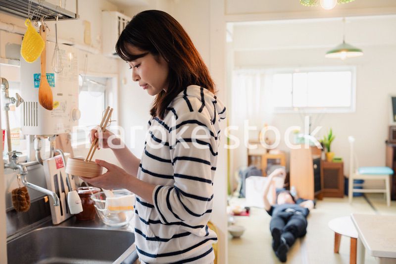 妻がお弁当を作っている後ろで寝転ぶ夫