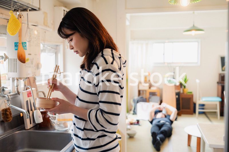 妻がお弁当を作っている後ろで寝転ぶ夫