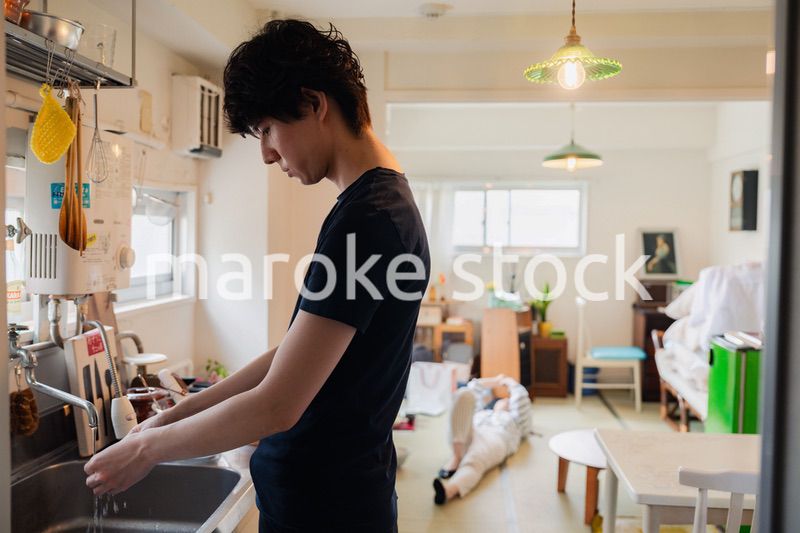 家事をする夫と後ろでサボる妻