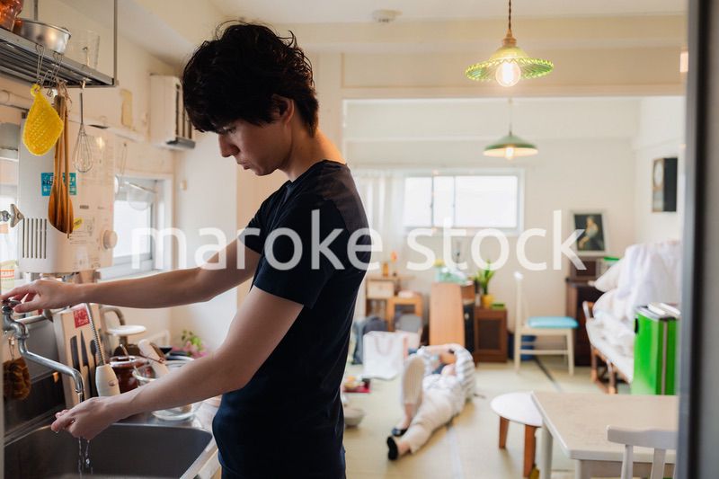 家事をする夫と後ろでサボる妻