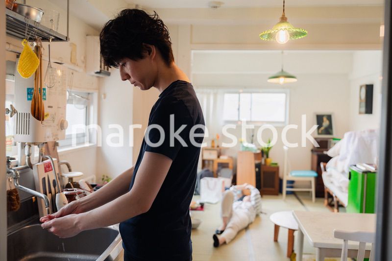 家事をする夫と後ろでサボる妻