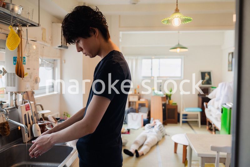 家事をする夫と後ろでサボる妻