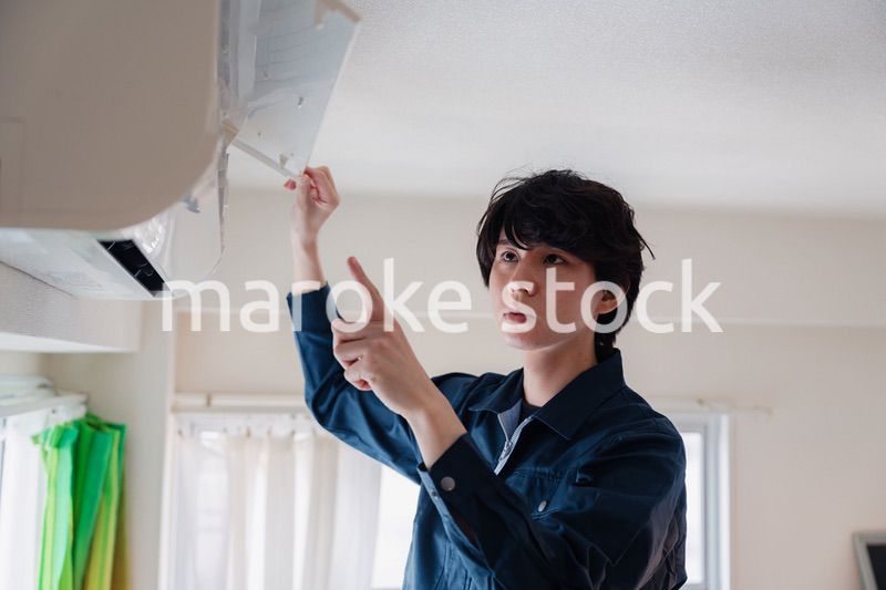 エアコンの点検をする男性