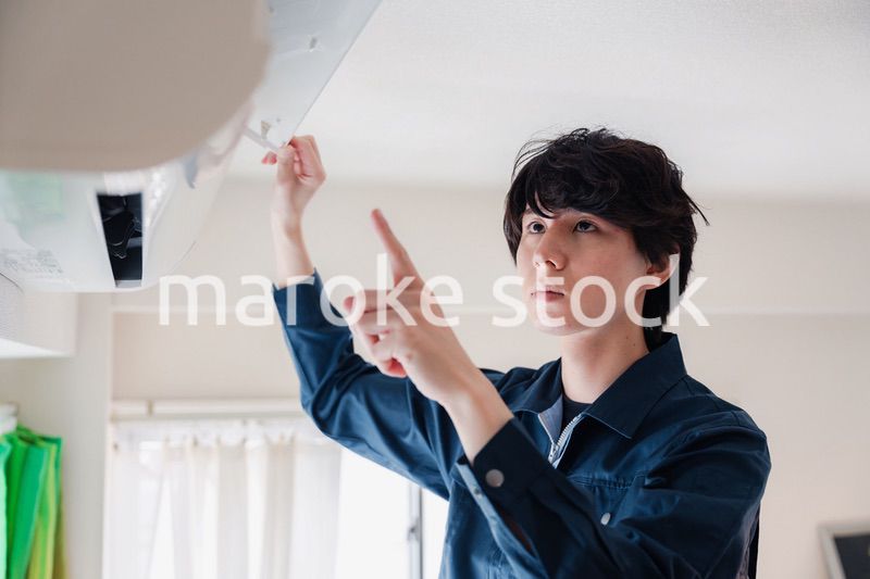 エアコンの点検をする男性