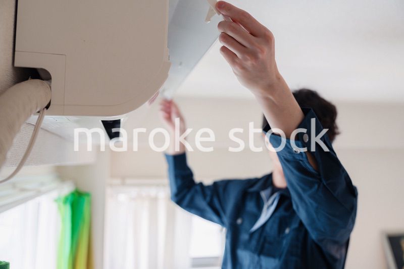 エアコンの点検をする男性