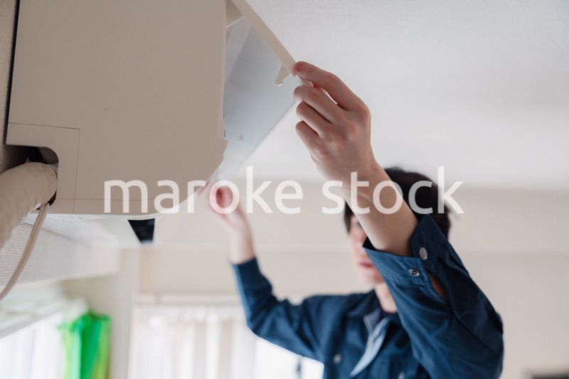 エアコンの点検をする男性