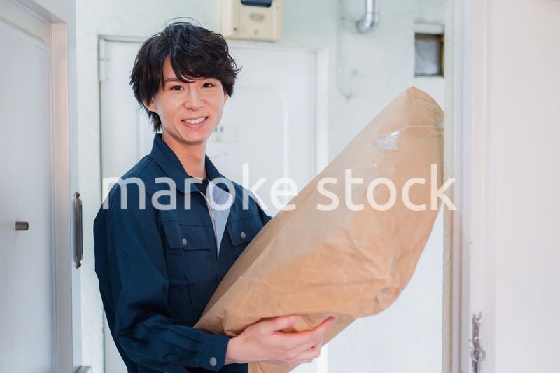 古いマンションに荷物を届ける男性